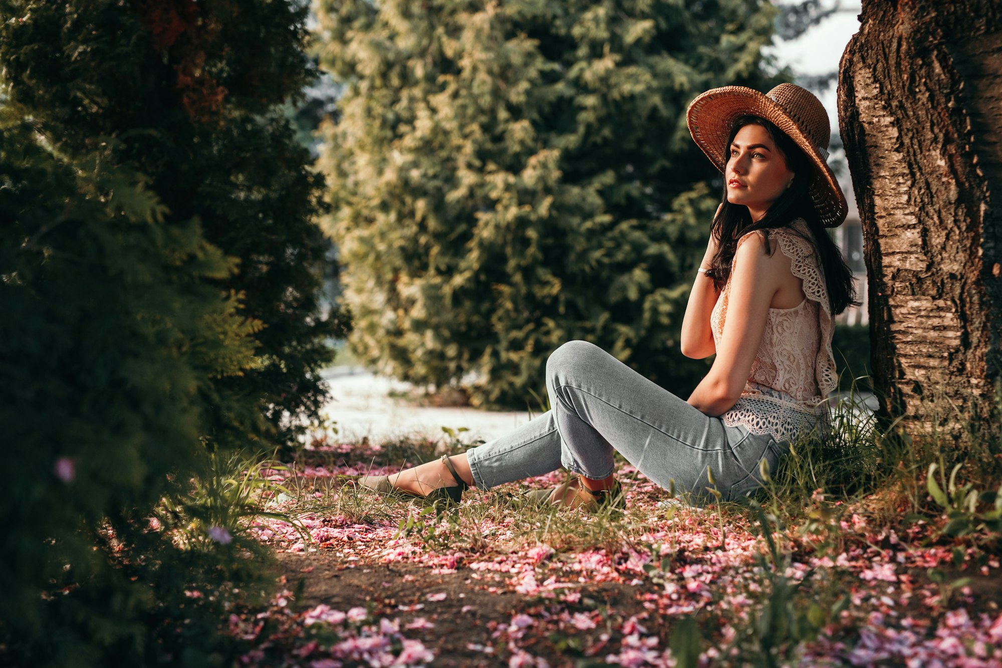 Relaxed woman in hat sitting under tree in garden